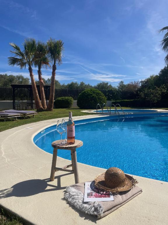 a bottle of wine sitting on a table next to a swimming pool at Authentic Villa with amazing pool in Santa Gertrudis de Fruitera