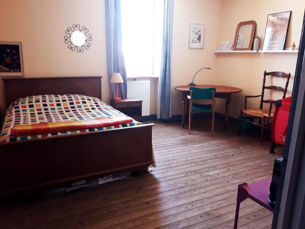 a bedroom with a bed and a table and chairs at Quartier De La Madeleine in Sorges