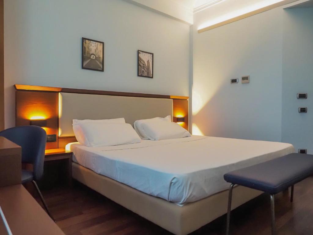 a bedroom with a large bed and two chairs at Dado Hotel International in Parma