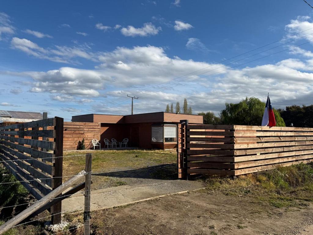 a fence in front of a house with a flag at Alojamiento casa, campo Angol in Huequén