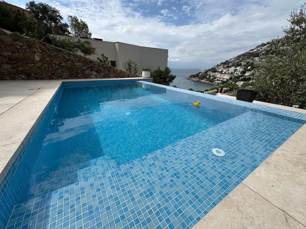 a blue swimming pool with a view of the ocean at Preciosa casa con piscina desbordante y vistas al mar in Roses