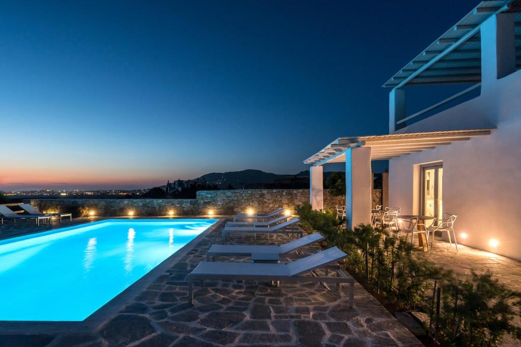 a villa with a swimming pool at night at Seven Suites in Glinado Naxos