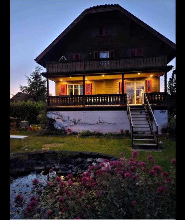 a large house with a porch and stairs to it at Holzchalet mit Garten in Egnach