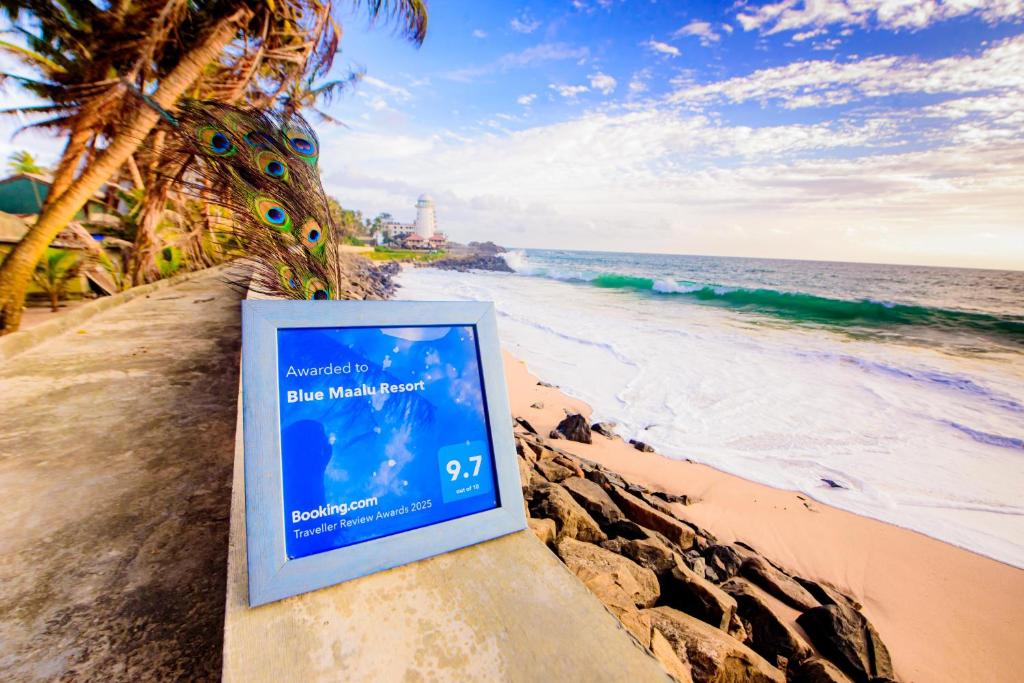 a sign on a wall next to the beach at Blue Maalu Resort in Ambalangoda