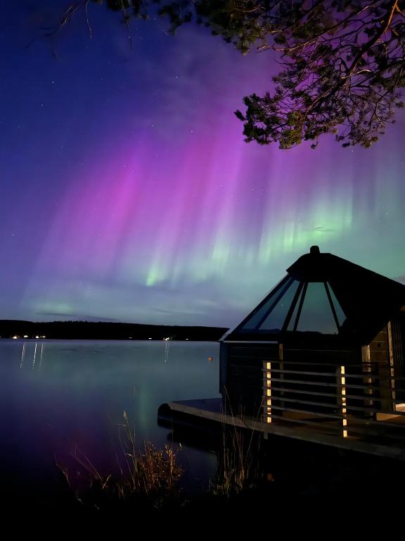 an image of the aurora over a lake with a tent at LakeLodge Kiehinen & Igloos in Rovaniemi