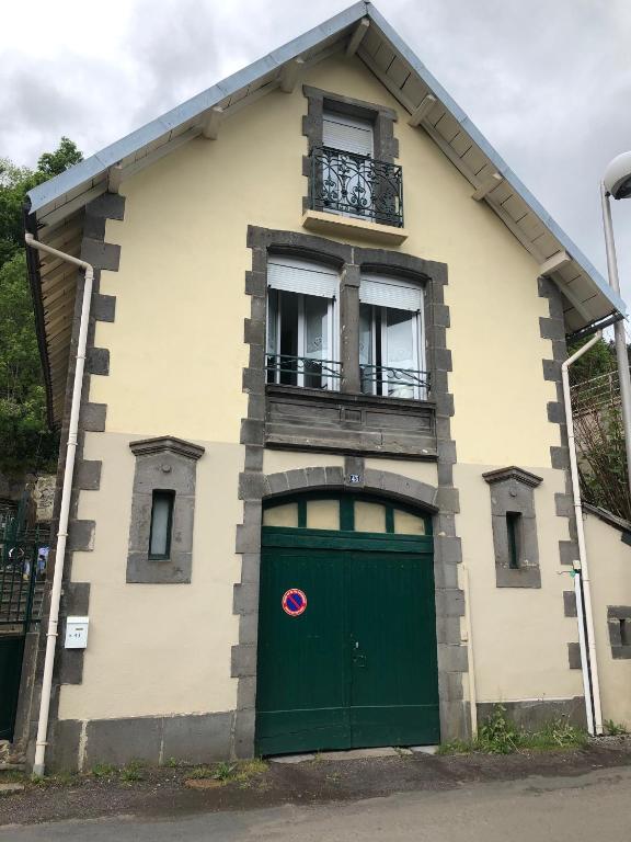 a building with a green door and a balcony at VILLA LOZELOUX n 2 in Le Mont-Dore