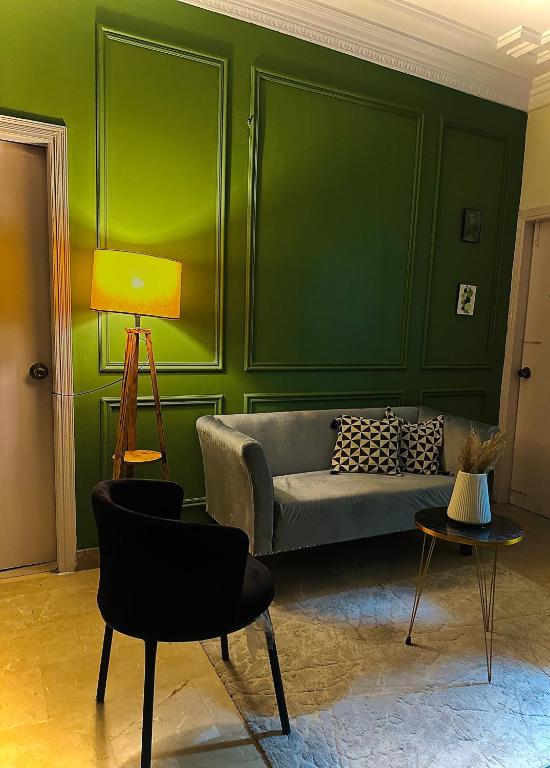 Una sala de estar con un sofá y una pared verde. en The Haven, en Karachi