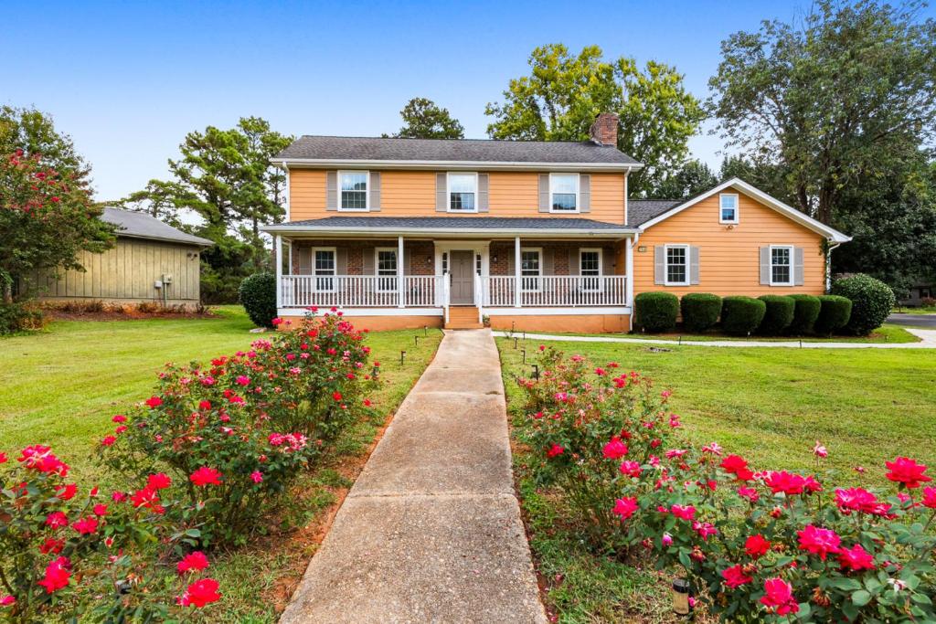 a house with red flowers in the yard at Lilburn Gateway with Game Loft, Fire Pit, Stone Mountain in Snellville