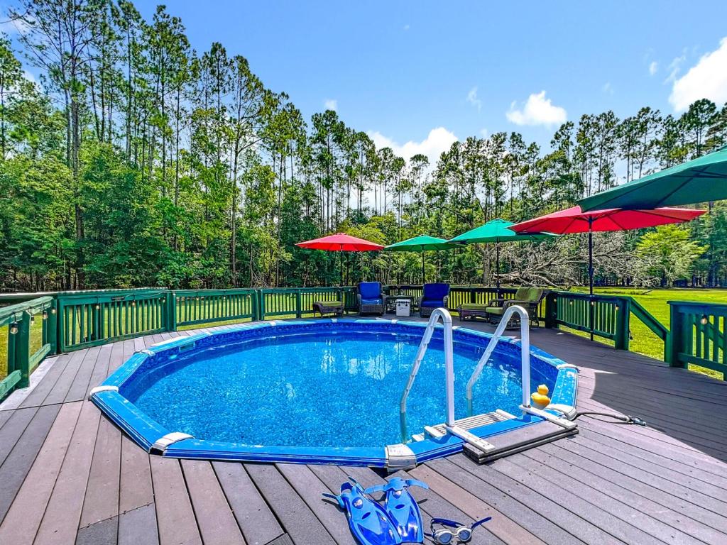 einen Pool auf einer Holzterrasse mit Sonnenschirmen in der Unterkunft Cabin Retreat on 8.5 Acres at High Springs, FL in High Springs