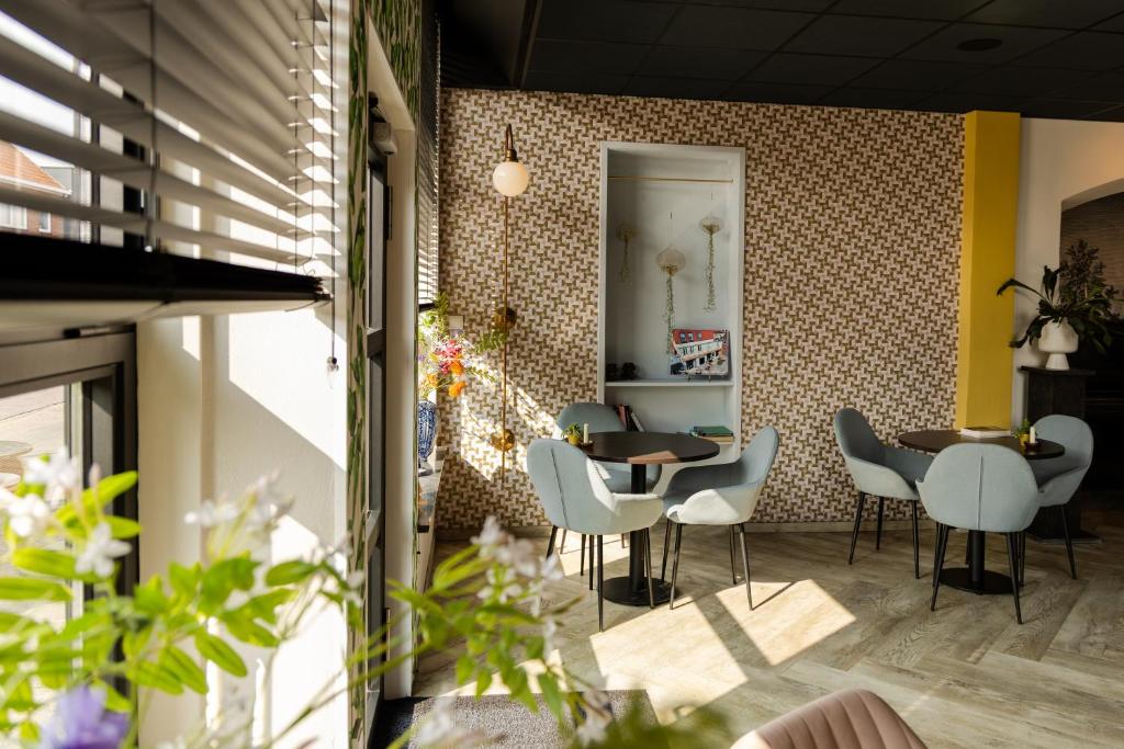 a dining room with tables and chairs and a wall at Boutique Hotel Charley's in Westkapelle