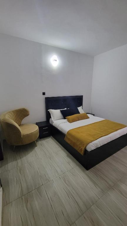a bedroom with a large bed and a chair at Seven kings apartment Lekki in Araromi