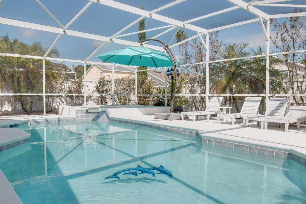 a swimming pool with chairs and an umbrella at Magic Retreat Orlando in Davenport