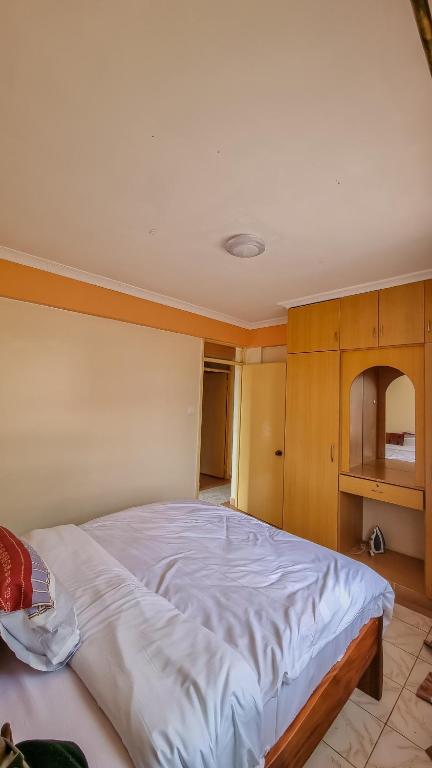 1 dormitorio con 1 cama blanca grande y armarios de madera en Rubz family home, en Nairobi