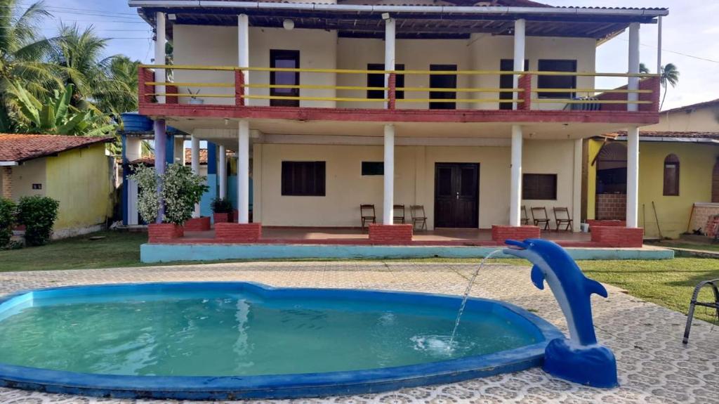 a pool in front of a house with a fountain at Pousada Encantos de Paripueira in Paripueira
