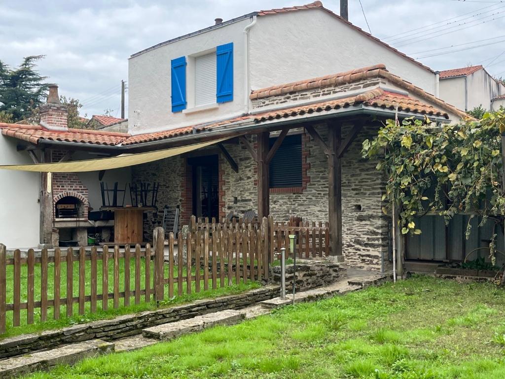 Casa con ventanas azules y valla de madera en Chez Jean-Jean, en Chantonnay