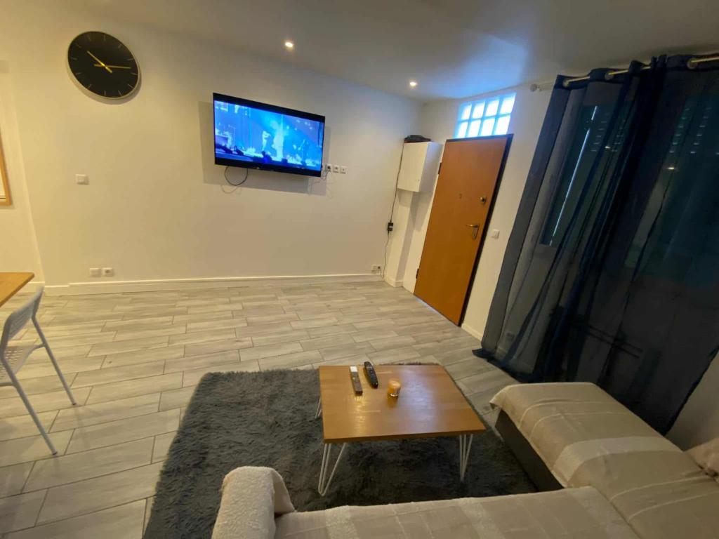 Una sala de estar con un sofá y un televisor en la pared. en Zola Saint Ouen, en Saint-Ouen