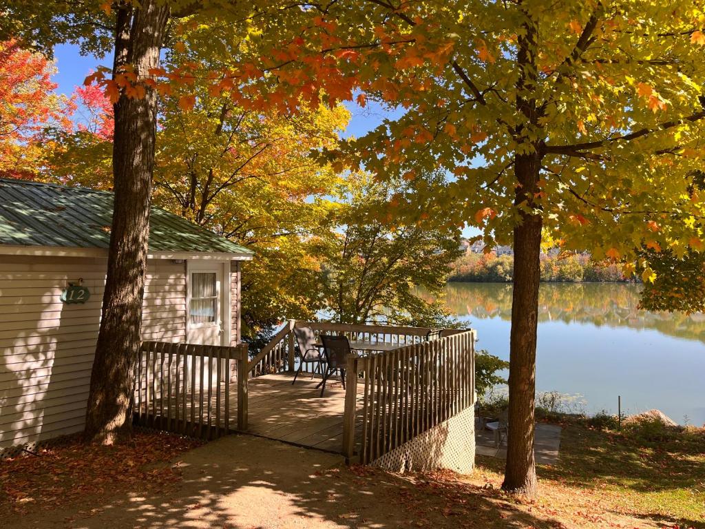 una casa con un porche con una valla al lado de un lago en Camping Chalets Lac St-Augustin, en Quebec
