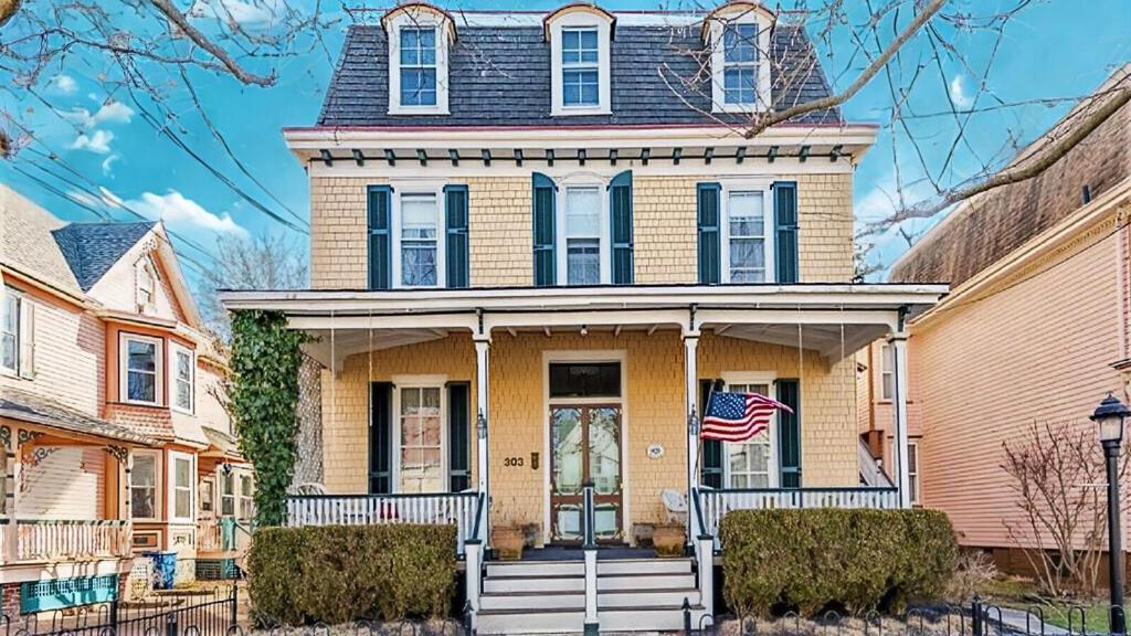 une maison jaune arborant un drapeau américain dans l'établissement Lillys Butterscotch Cottage-5 Bdrm Wbonus Loft!!, à Cape May