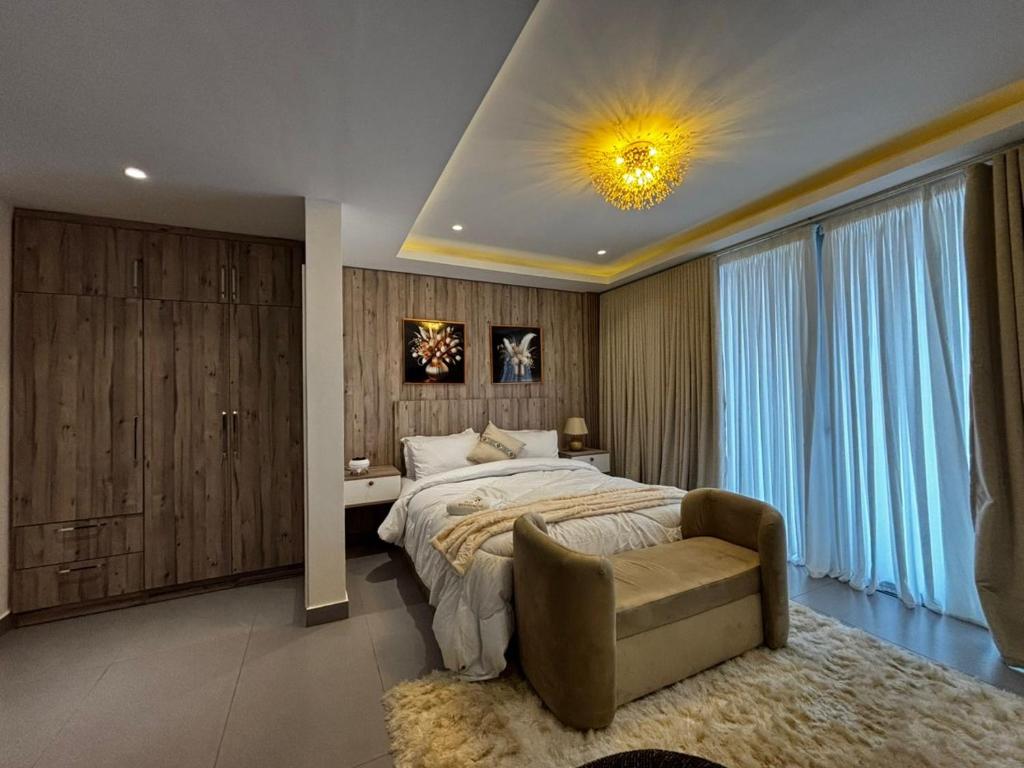 a bedroom with a bed and a chair in a room at Ensuite studios luxury apartment Pool and balcony in Accra