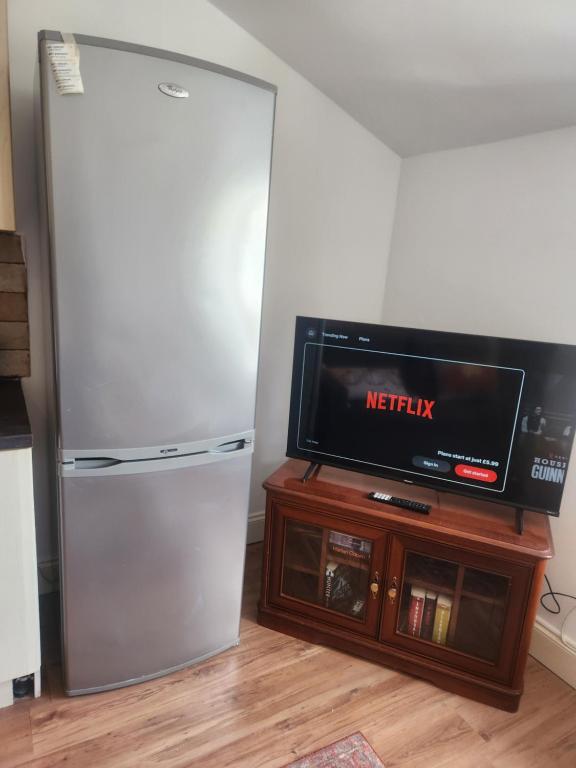 a refrigerator and a tv in a room at Stylish Flat on Cowley a Walk to Oxford Centre in Oxford