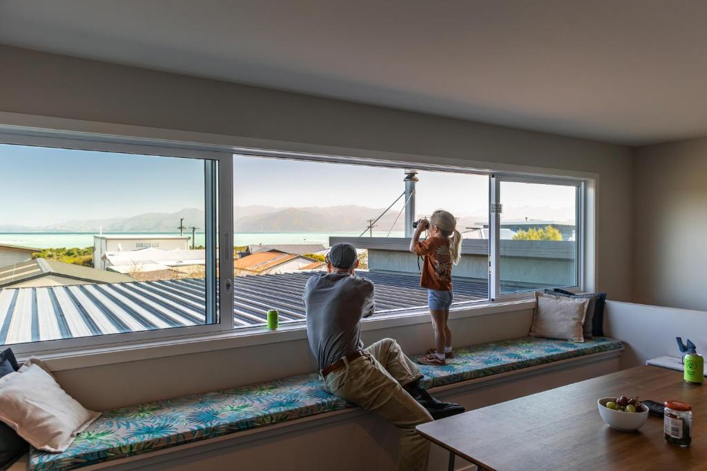 Dos personas mirando por la ventana de una casa en Ocean Outlook - KK2565, en Kaikoura