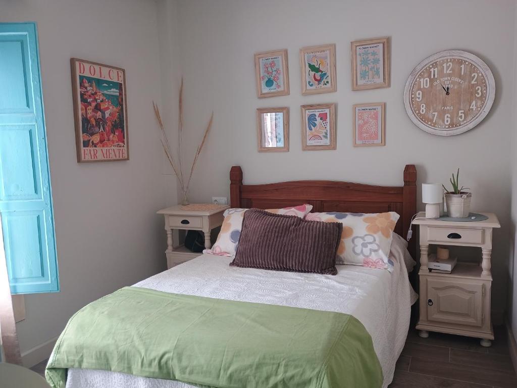 Un dormitorio con una cama y un reloj en la pared. en El nido del dragón, en Carratraca