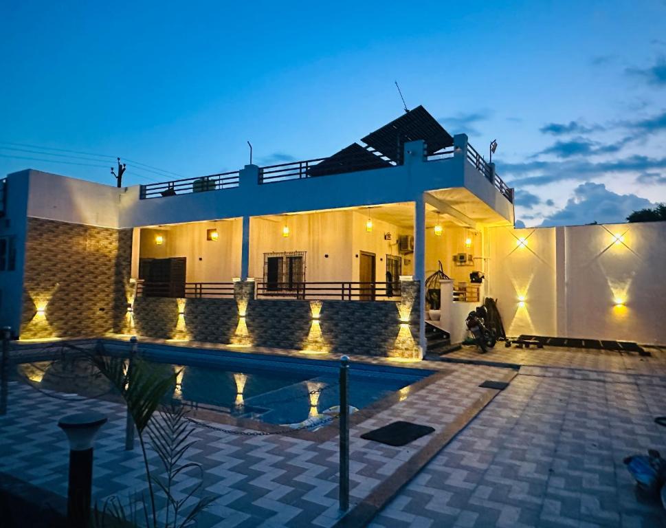 a villa with a swimming pool at night at Aruna Farm House in Kakarmatha