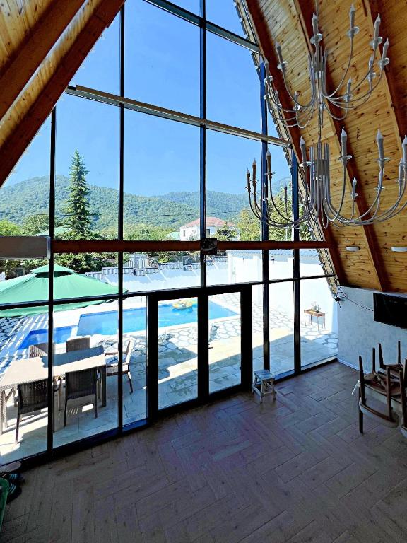 a large room with a table and chairs and windows at A-Frame Chalet with Hot Pool in Gabala