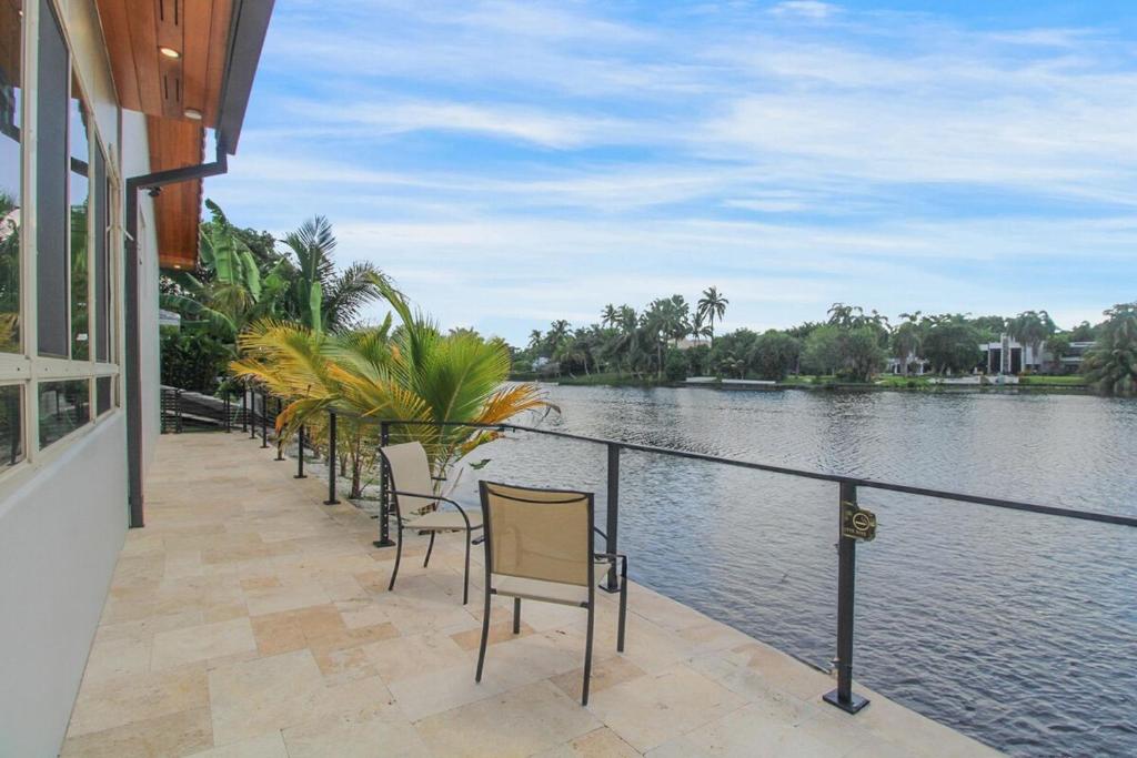 una fila de sillas sentadas junto a un cuerpo de agua en Vista Azul Lake Front Home with Hot Tub and Swim Spa, Fishing Dock, Gym, Game Room with Darts, Ping Pong, A Pool Table and more!, en Miami Lakes