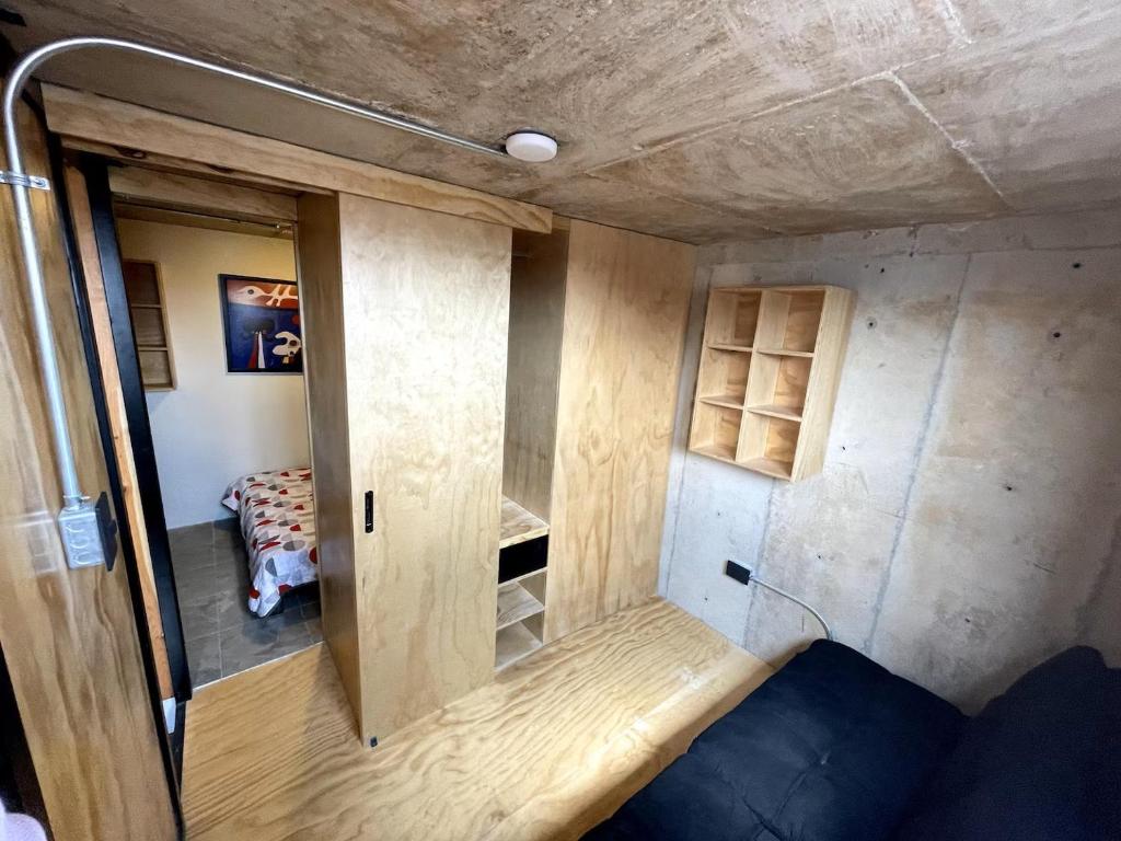 a small room with a bed and a door in a room at Living Universidad in El Gallinero
