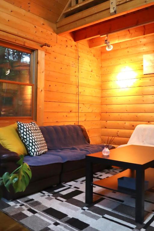 a living room with a couch in a wooden room at Secret Base Mysa シークレットベース ミーサ 星の街399 in Tsumagoi