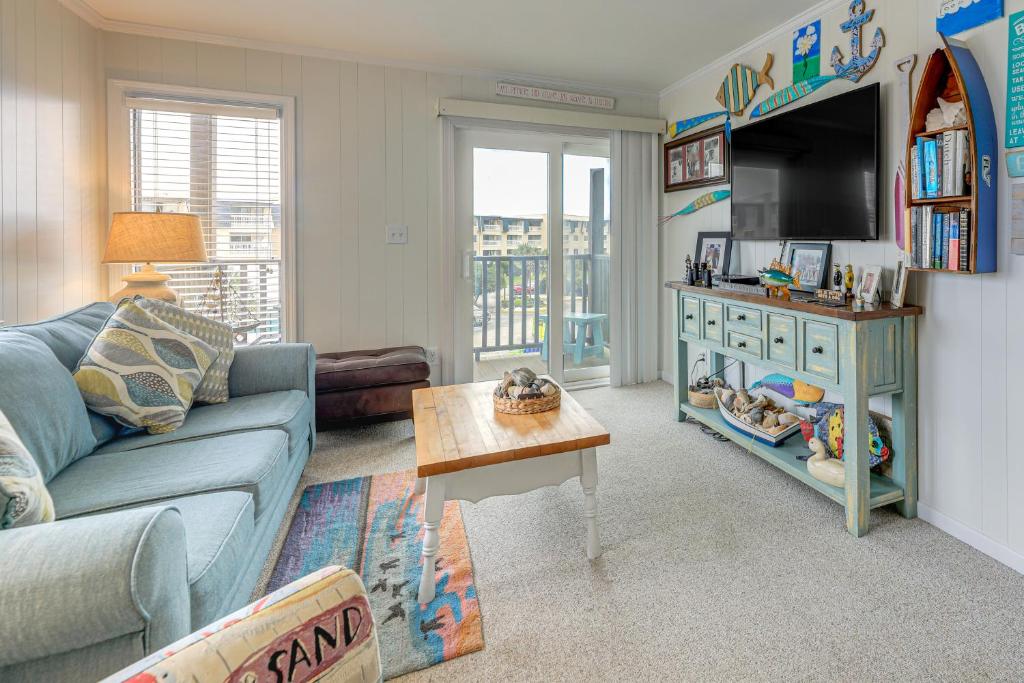a living room with a blue couch and a tv at Steps to Sand! Condo with 2 Pools in Atlantic Beach in Atlantic Beach