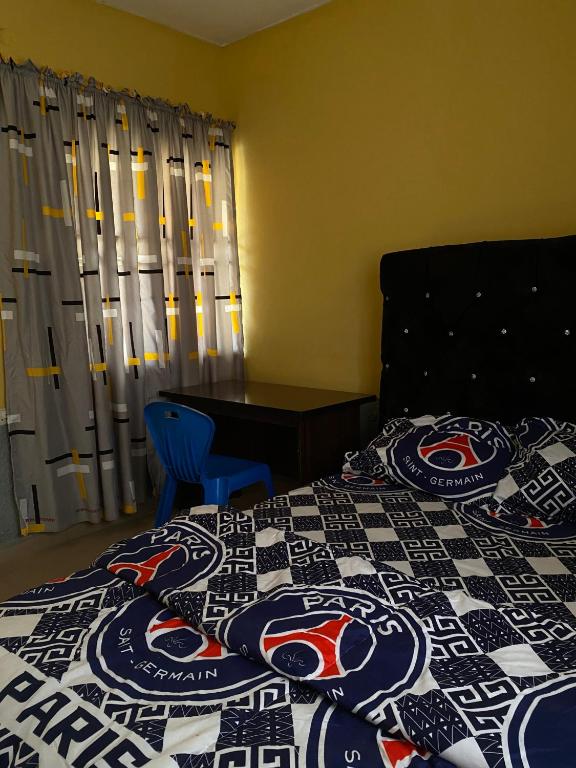 Ado EkitiにあるAlidiat Apartmentsのバッファロー・ビルズのキルトが敷かれたベッドのある寝室