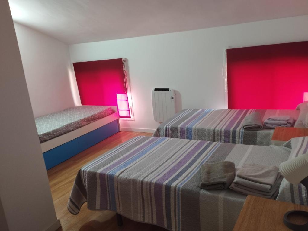 two beds in a room with red lights at Apartamentos calatorao in Calatorao