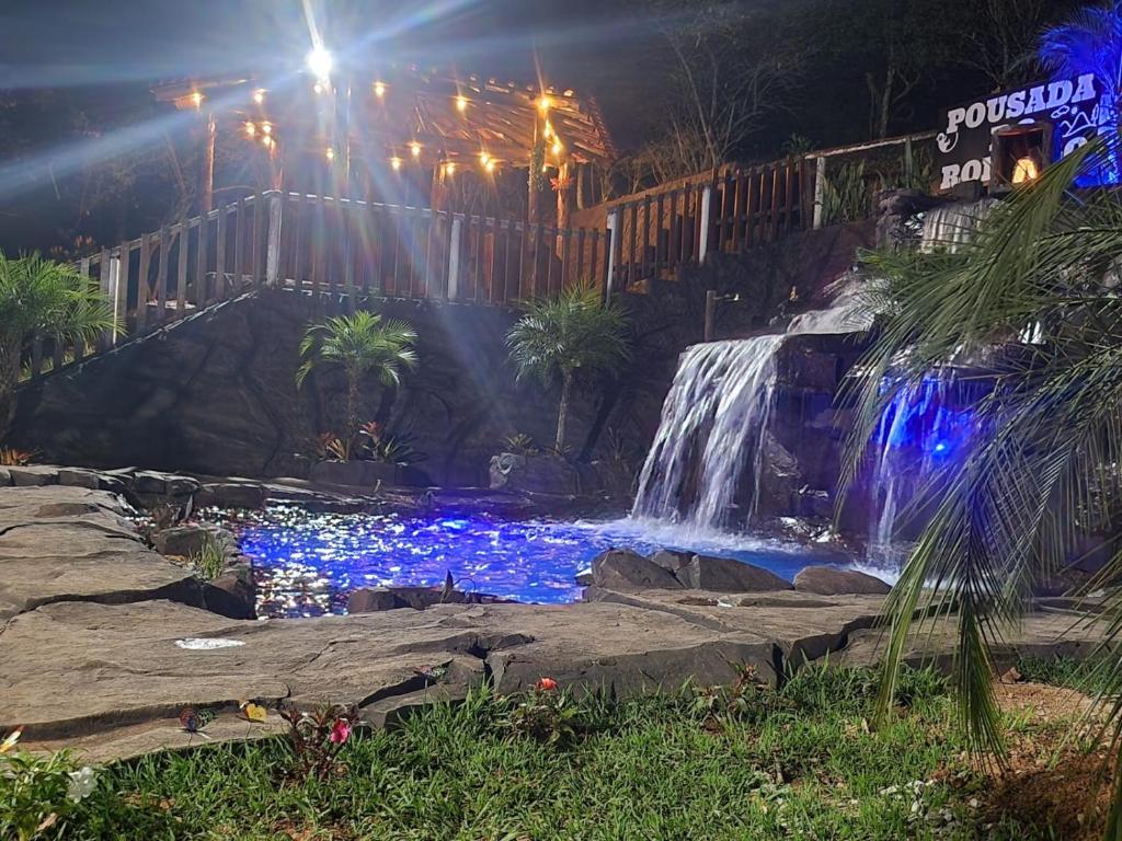 a waterfall and a pond with blue lights at Pousada do Rodrigo in Macacos