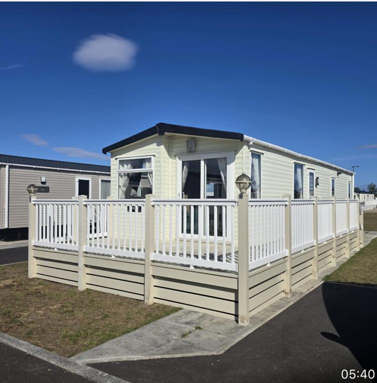 a white mobile home with a white fence at Spacious Modern Seaside Caravan in Lossiemouth