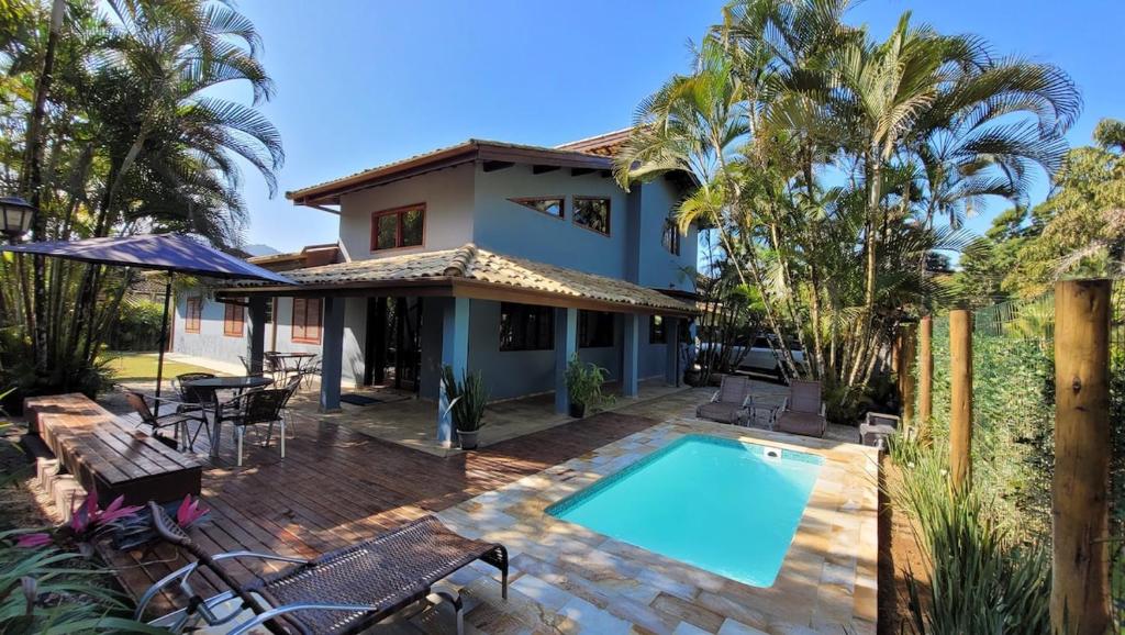 a house with a swimming pool and palm trees at Casa em Itamambuca com piscina em frente a praia in Ubatuba