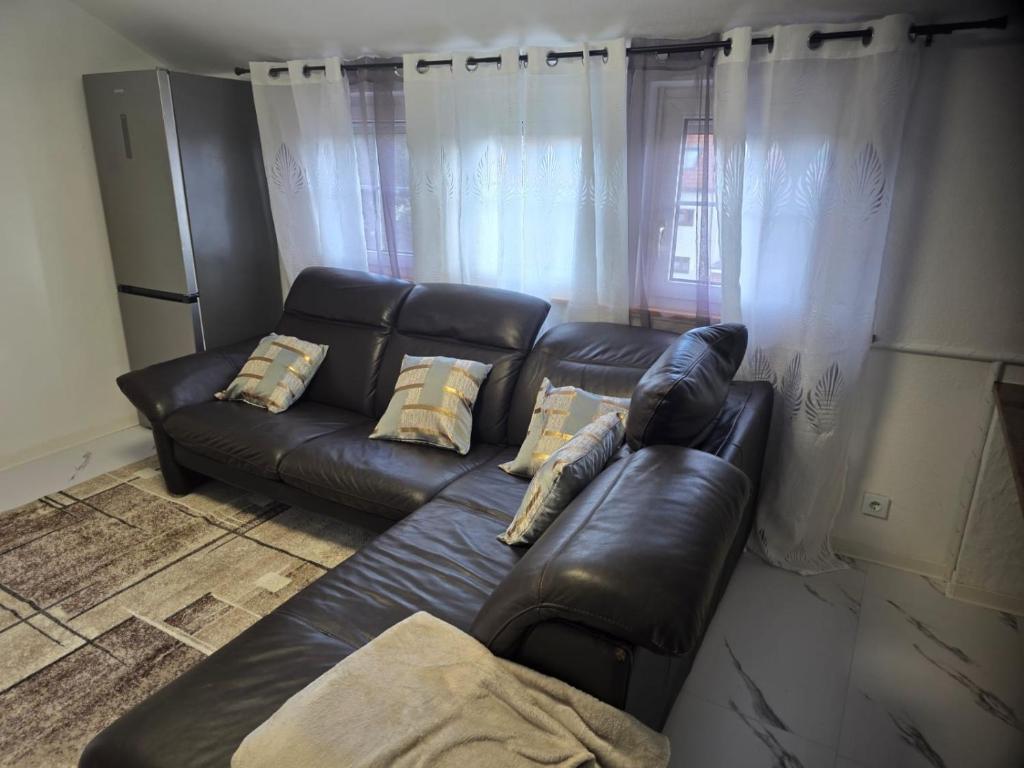 a living room with a black leather couch and a window at S&P Dream Apartment in Backnang