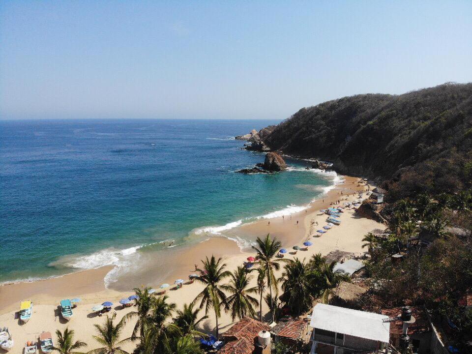 a beach with a bunch of umbrellas and the ocean at Casa Estrella Fugaz Rinconcito Mazunte in Santa María Tonameca
