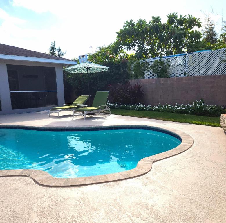 a swimming pool with two chairs and an umbrella at Private Oasis!Bike to beach, heated pool in Naples