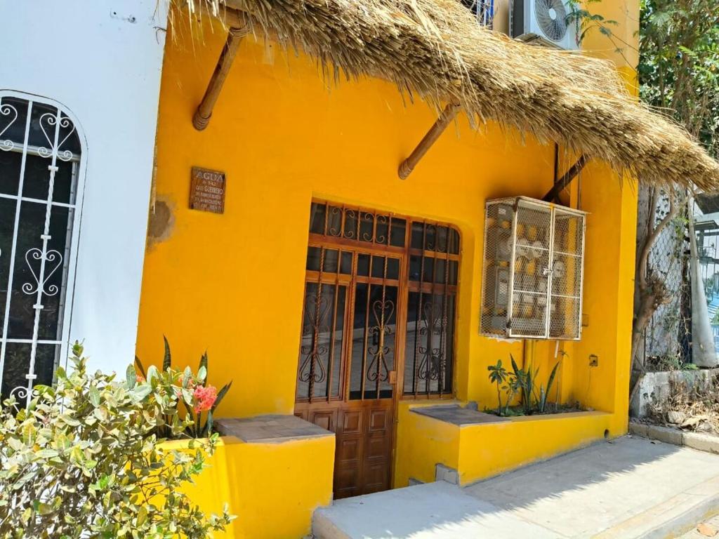 une maison jaune avec toit de chaume dans l'établissement Casa Maya Punta Zicatela, à Brisas de Zicatela