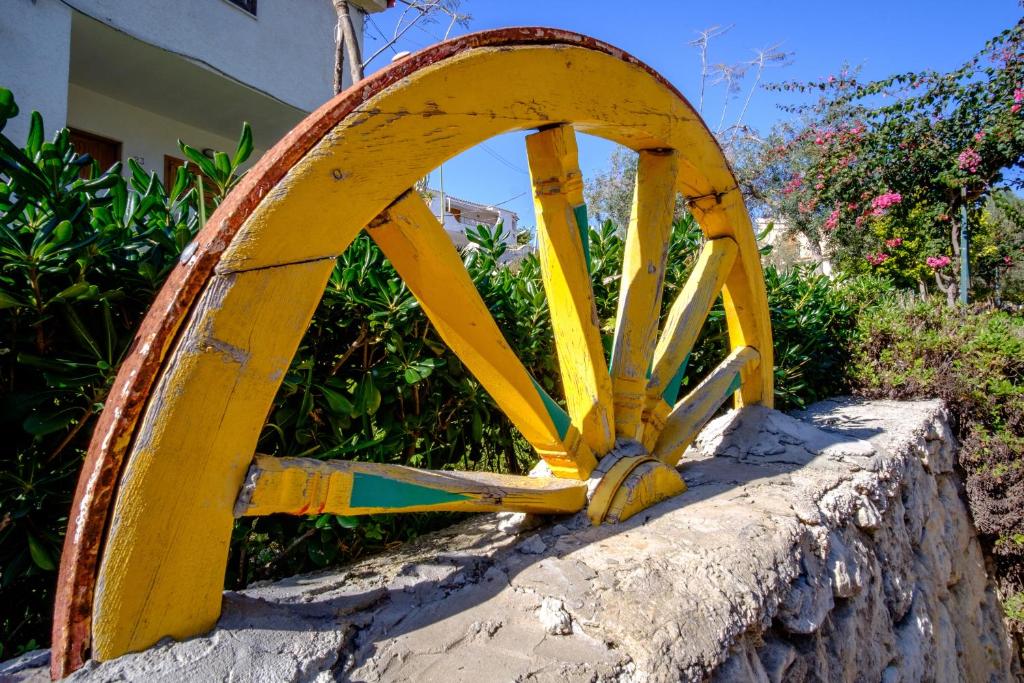 a yellow wooden wheel sitting on a stone wall at Dalle Grotte al Mare in Fontane Bianche