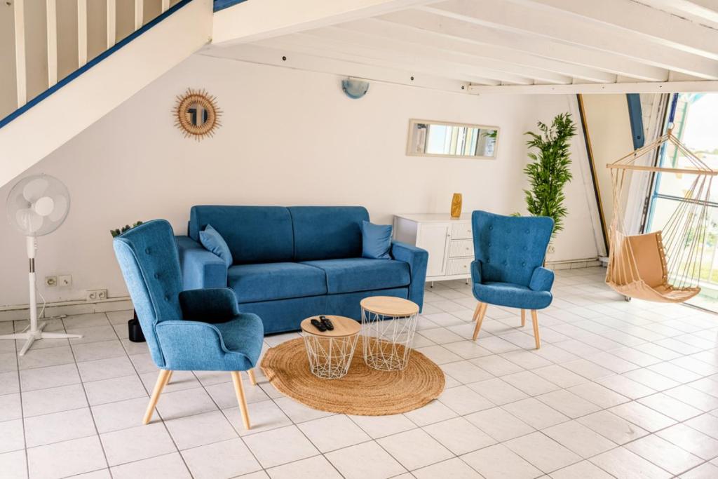 a living room with a blue couch and two chairs at COEUR de Sainte Anne-Appartement à 50 m de la PLAGE-vue MER-Clim in Sainte-Anne
