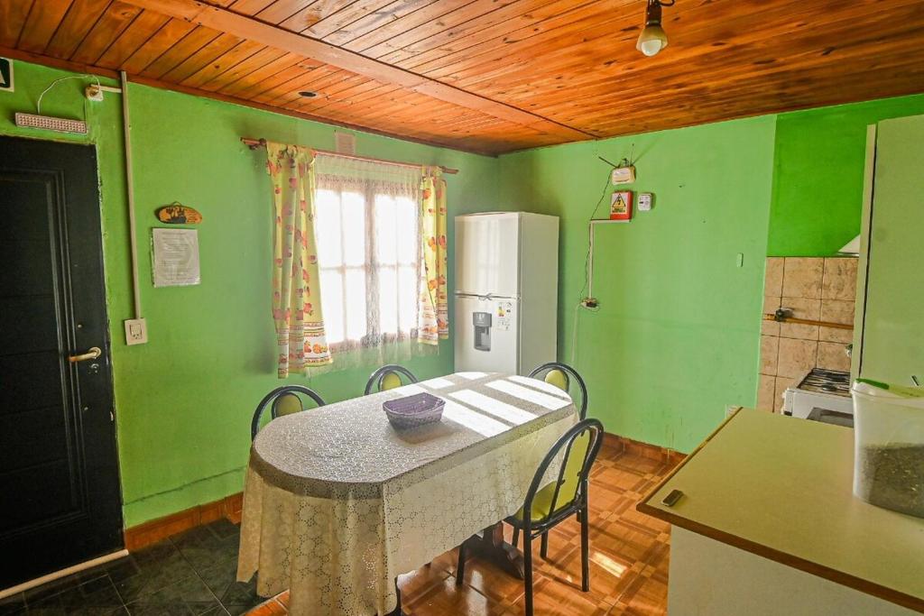 a kitchen with green walls and a table with chairs at Cabaña familiar cerca del mar en Caleta Olivia in Caleta Olivia