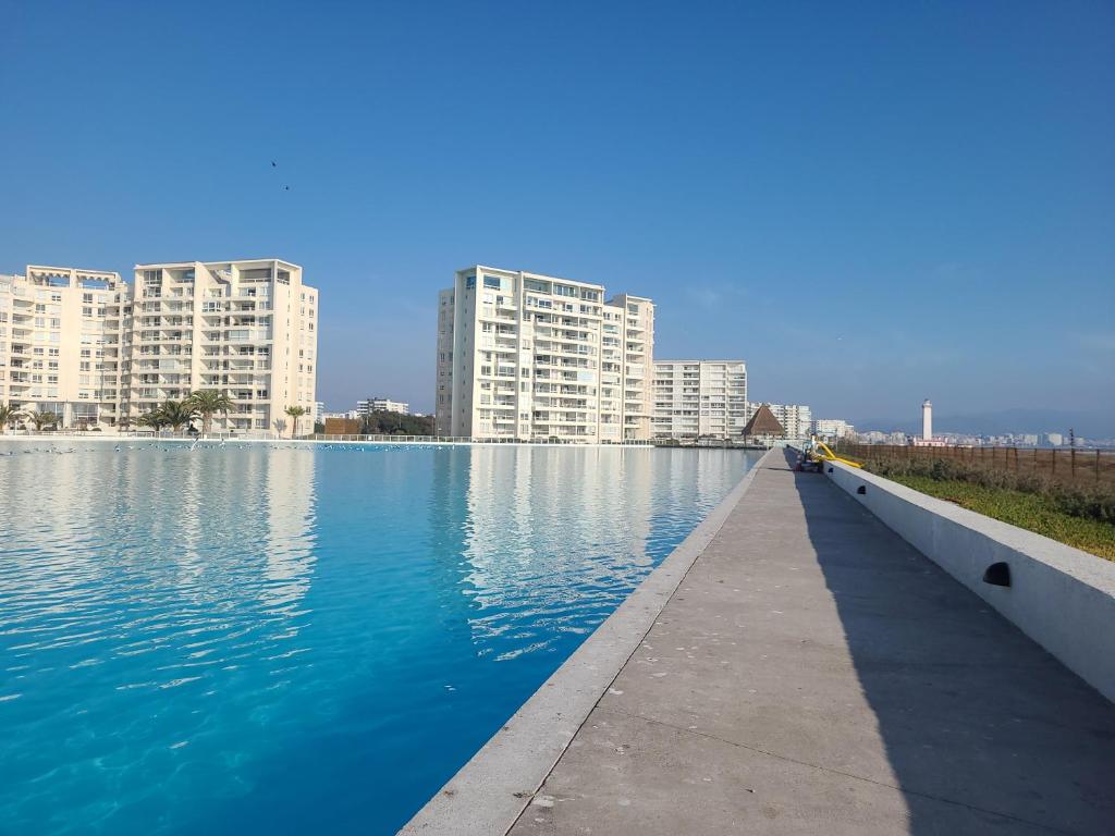 ein großer Wasserpool mit Gebäuden im Hintergrund in der Unterkunft Departamento Laguna del Mar in La Serena