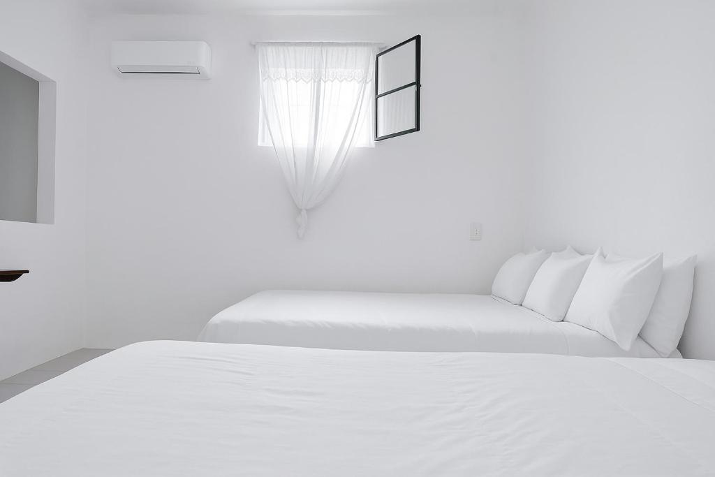 een witte slaapkamer met twee bedden en een raam bij Departamento Puerto Vallarta in Puerto Vallarta