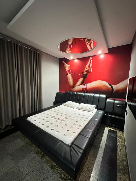 um quarto com uma cama e um quadro de uma mulher na parede em Motel Vitoria Reggia em São Vicente