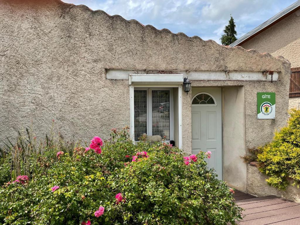 a building with a white door and pink flowers at Gîte chaleureux avec terrasse près de Nancy, parking privé, à proximité de festivals et nature - FR-1-584-9 in Domptail-en lʼAir