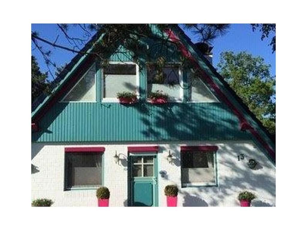 a white house with a green door and windows at 1-bedroom holiday home in Otterndorf