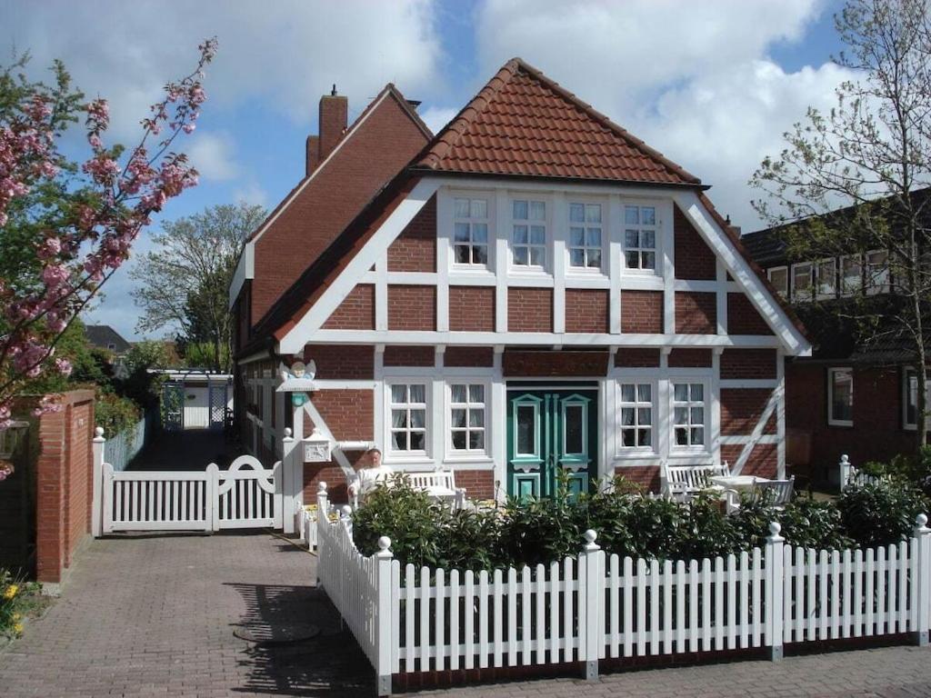 a red and white house with a white fence at 4 people North Sea East Frisian in Borkum
